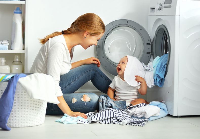 A imagem mostra uma mulher lavando as roupas e cobertas do seu bebê.